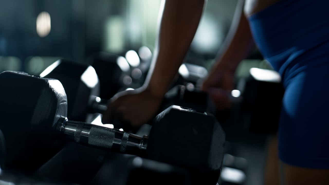 Member selecting dumbbells on the gym floor